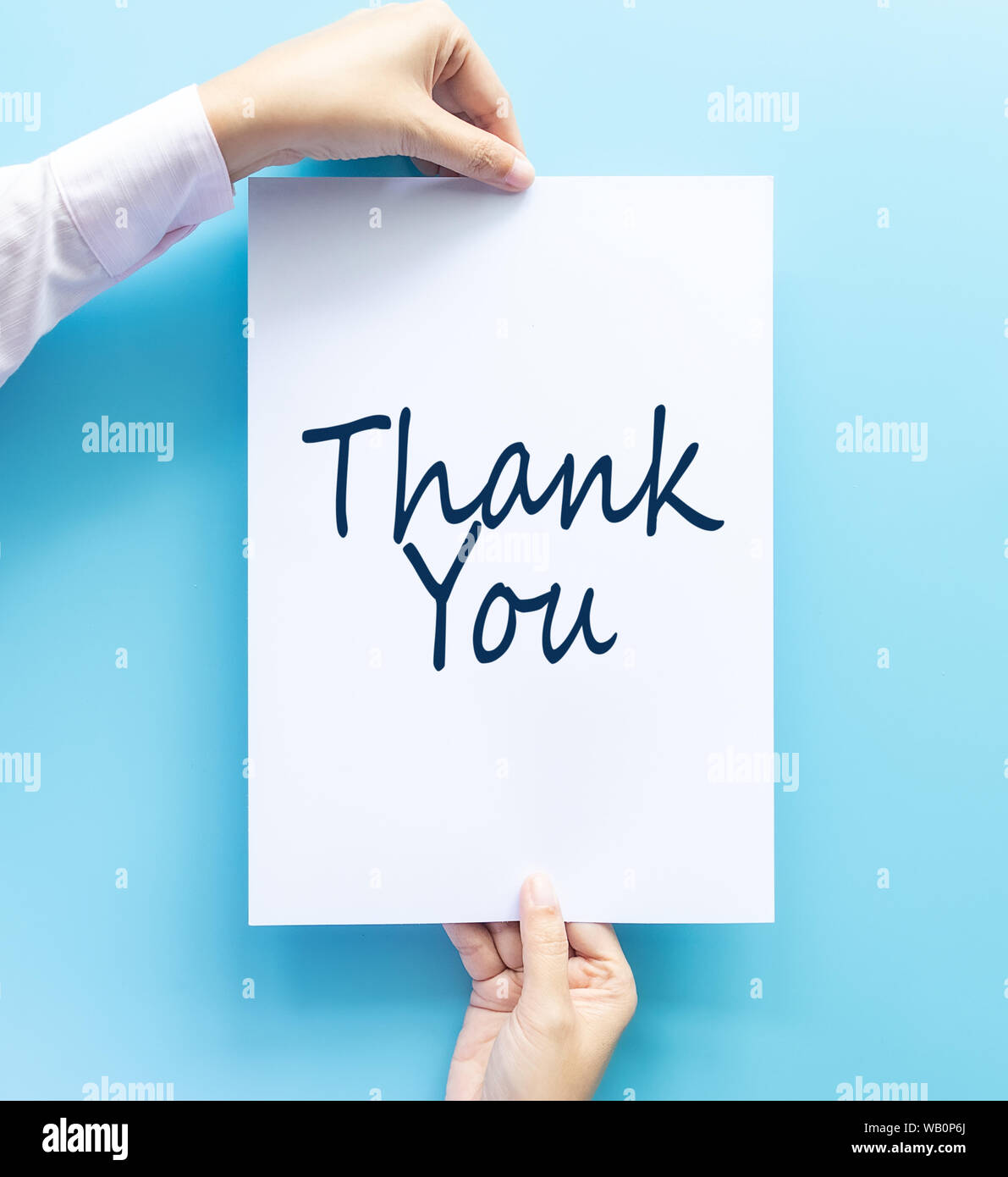 woman hand holding card with the word thank you isolated on blue background, studio shot Stock Photo