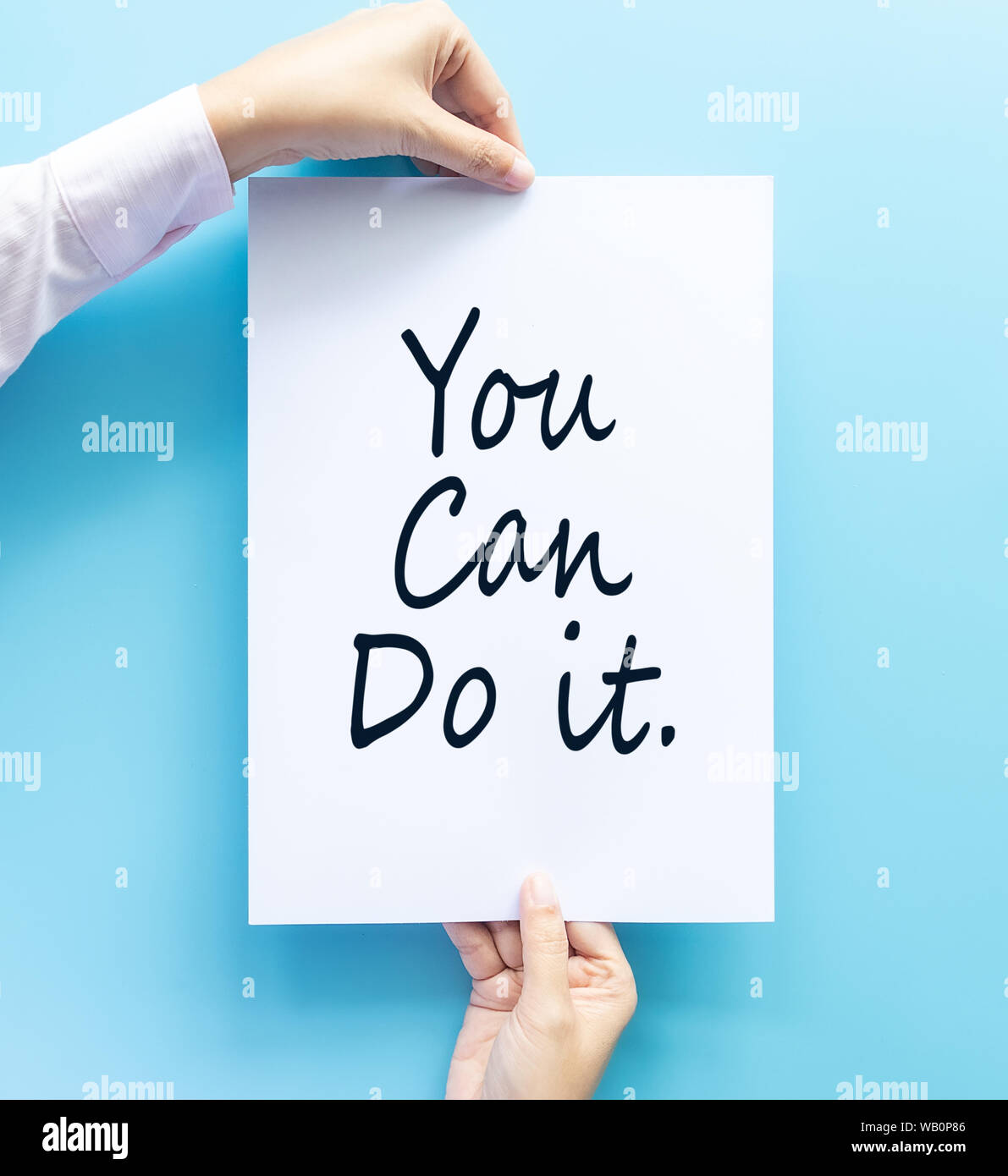 woman hand holding card with the word you can do it isolated on blue background, studio shot. cheer and support quote Stock Photo