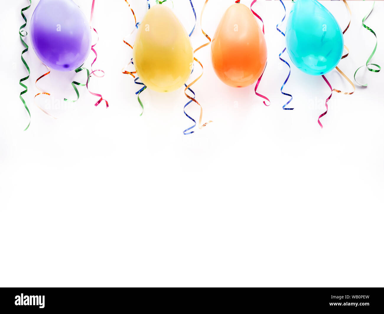 White wall decorated with balloons and streamers Stock Photo