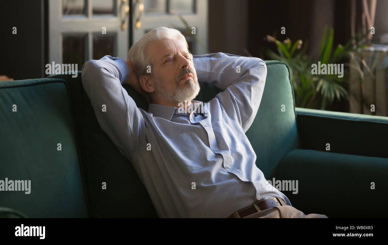 Calm elder senior man having daytime nap relaxing on couch Stock Photo