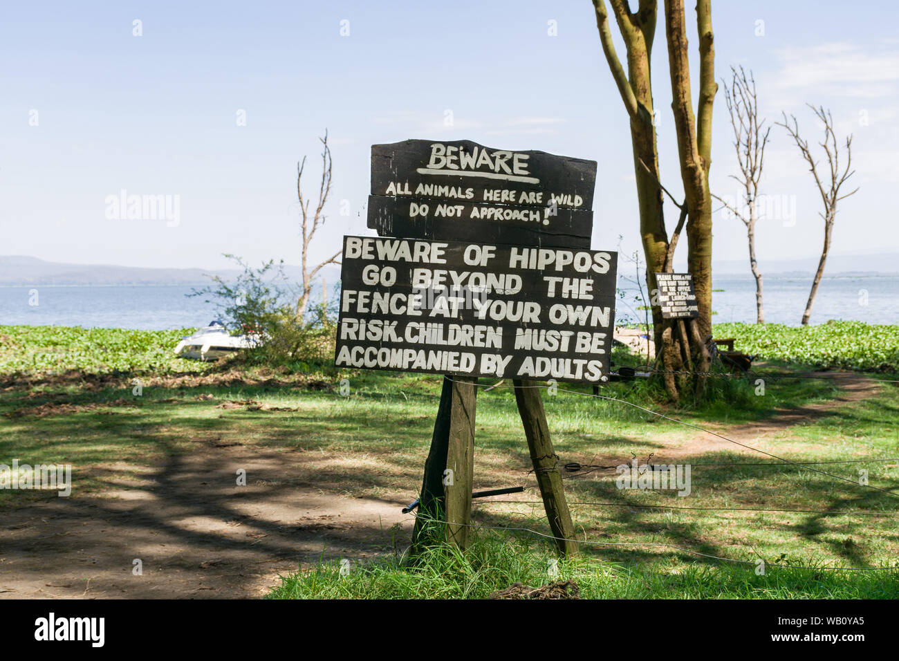 A large wooden sign with Beware of Hippos warning on it with lake Naivasha in background, Kenya Stock Photo