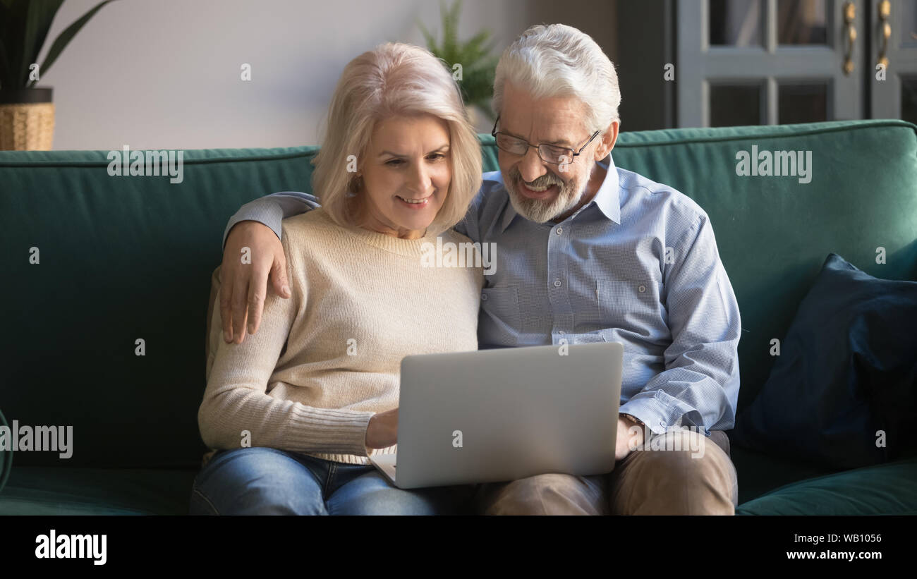 Happy old senior couple using laptop sit on sofa Stock Photo