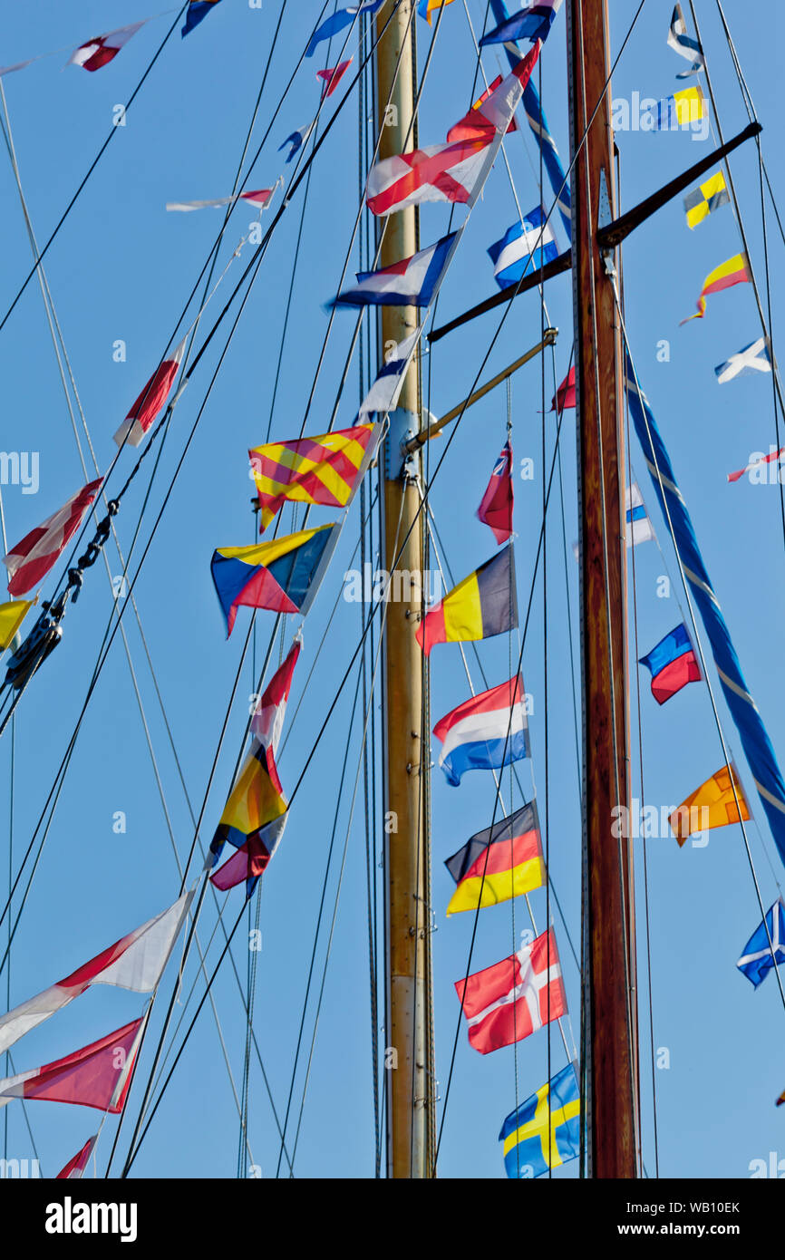 different international nautical flags on the mast of a sailing boat