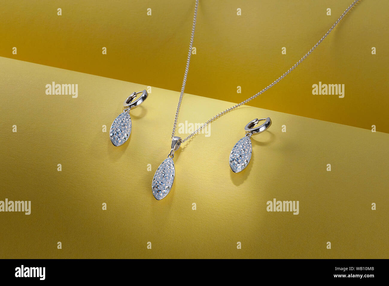 Silver earrings and pendant with stones on yellow background. Studio still life composition Stock Photo