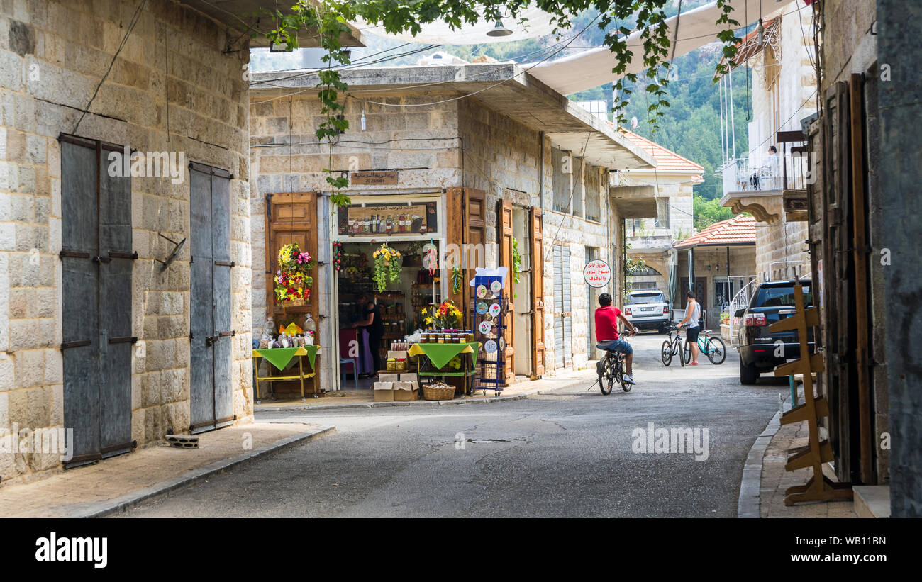Boy riding his bike past a local produce shop in the old souk of Douma, traditional Lebanese village, Lebanon Stock Photo