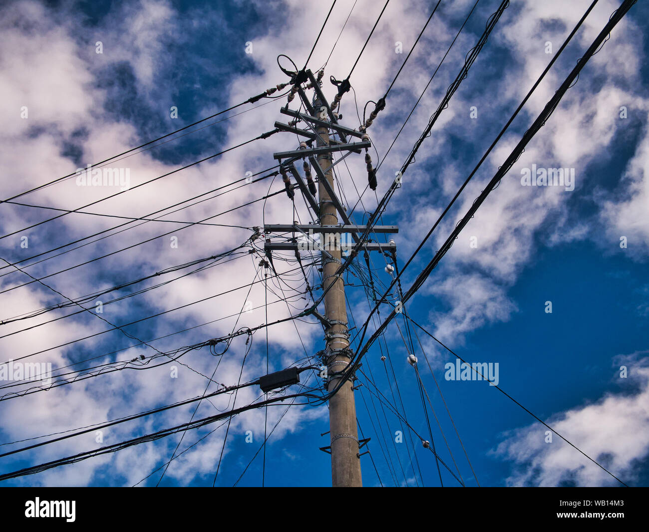 Highly loaded urban electricity pole showing many cables, taken in