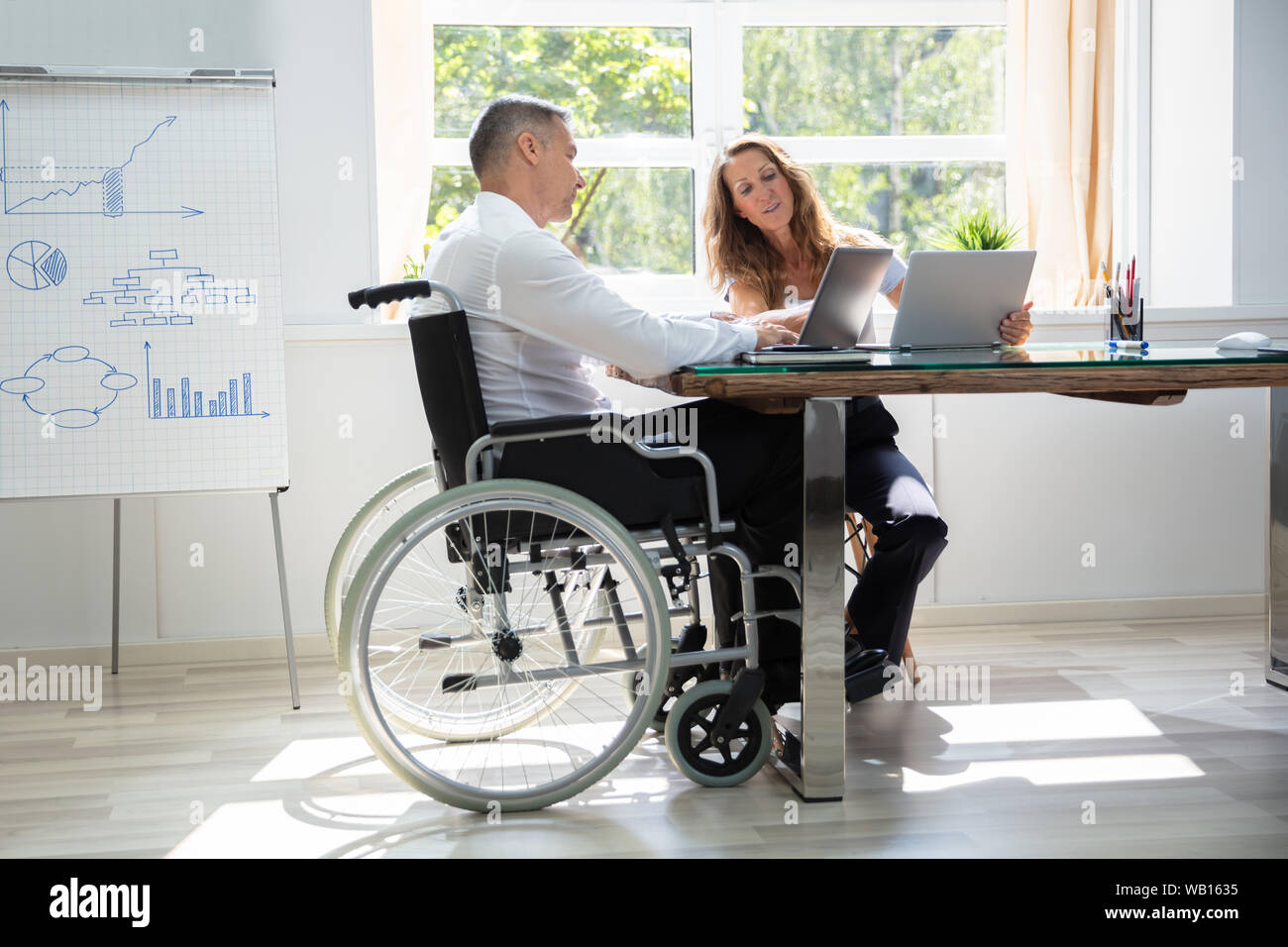 Two Workers Using Laptop Working Together At Office Stock Photo