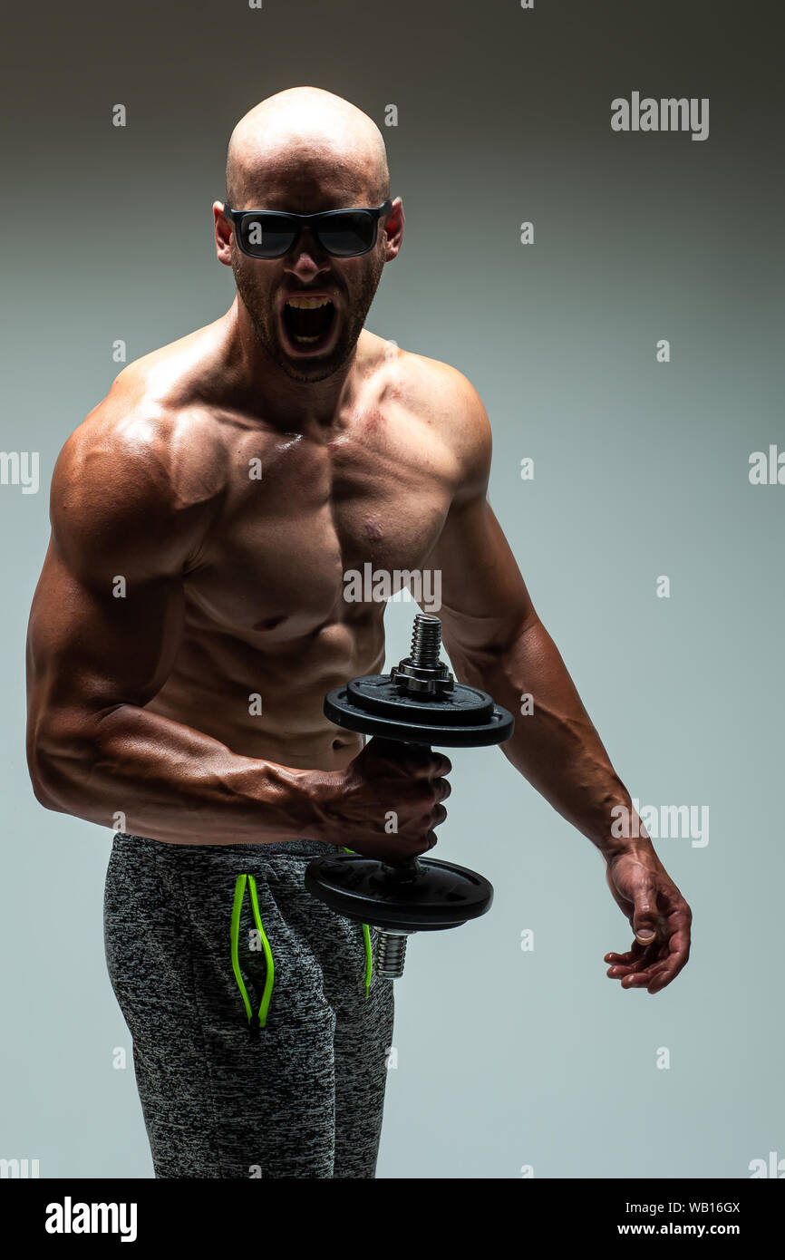 Strong young man bodybuilder performing exercise for biceps with heavy dumbbell in both hands Concept Artistic Gym Life Style Stock Photo