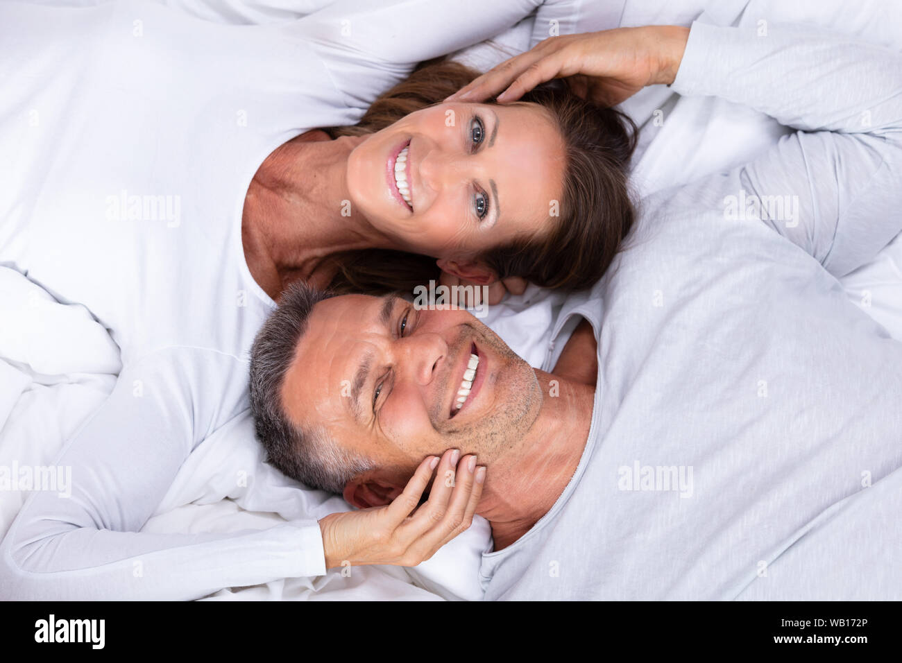 High Angle View Of Happy Mature Couple Lying On Bed Stock Photo
