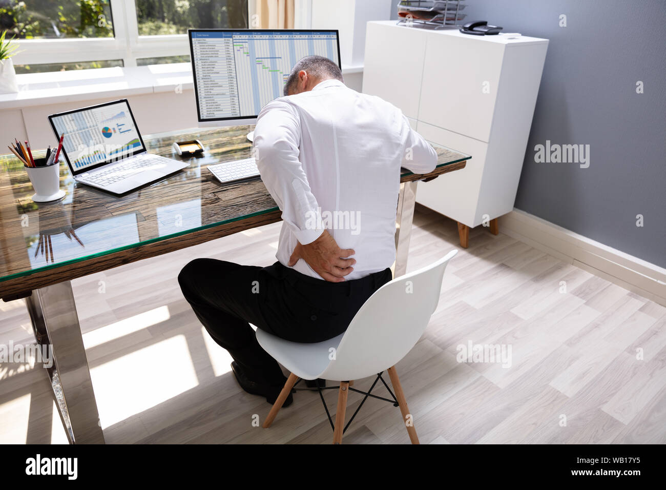 Businessman Suffering From Back Pain At Office Desk Stock Photo Alamy