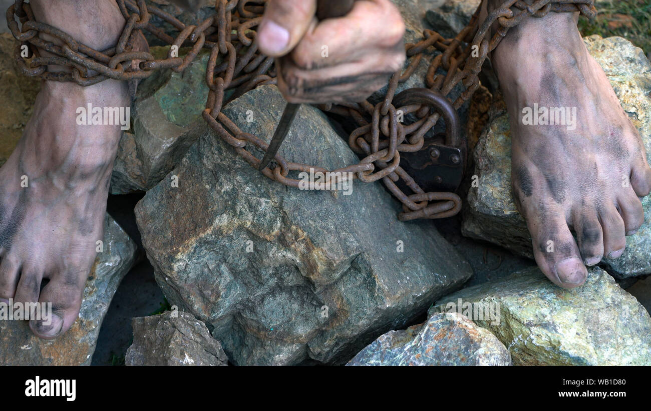 Hands and feet of a slave entangled in iron chains. An attempt to break