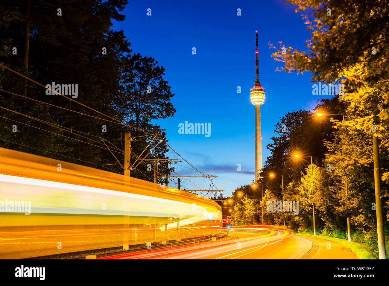 Germany, Stuttgart television tower and tramway illuminated by night at road with traffic and starry sky in summer surrounded by forest nature landsca Stock Photo