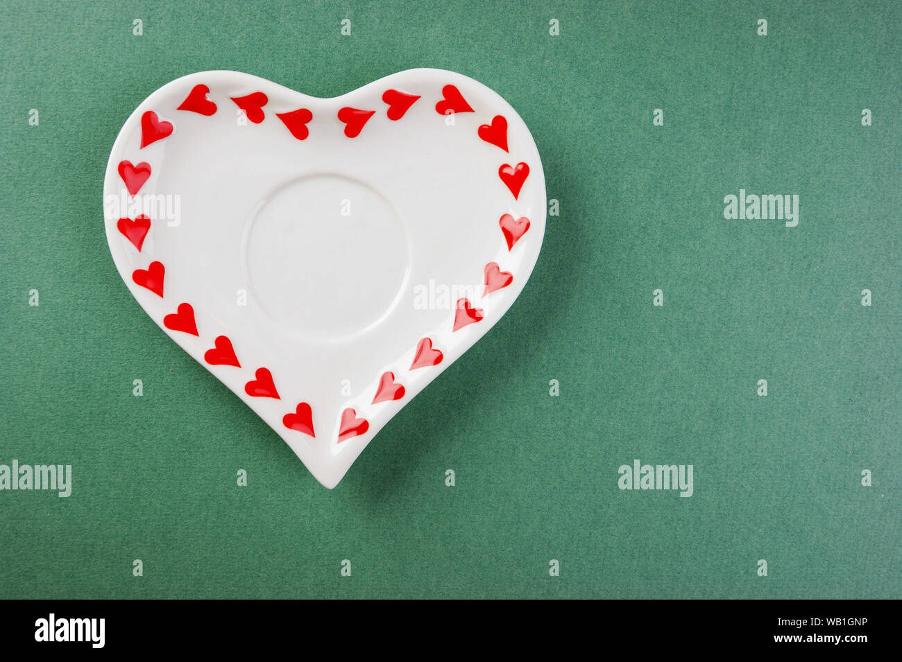 Heart form white plate on a green background Stock Photo - Alamy
