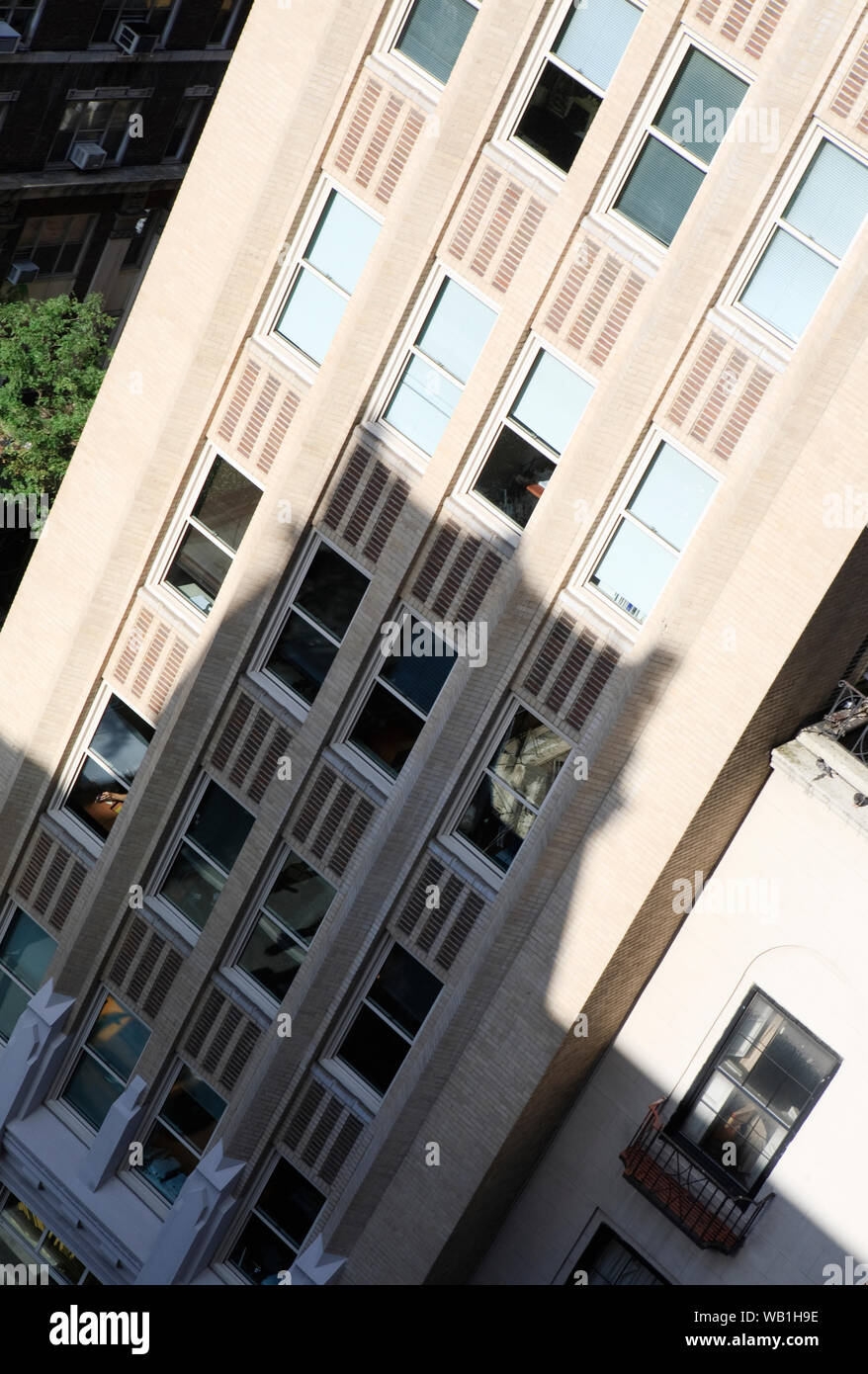 View looking down at an office block in Midtown Manhattan with a shadow cast on the sunlit building. Stock Photo
