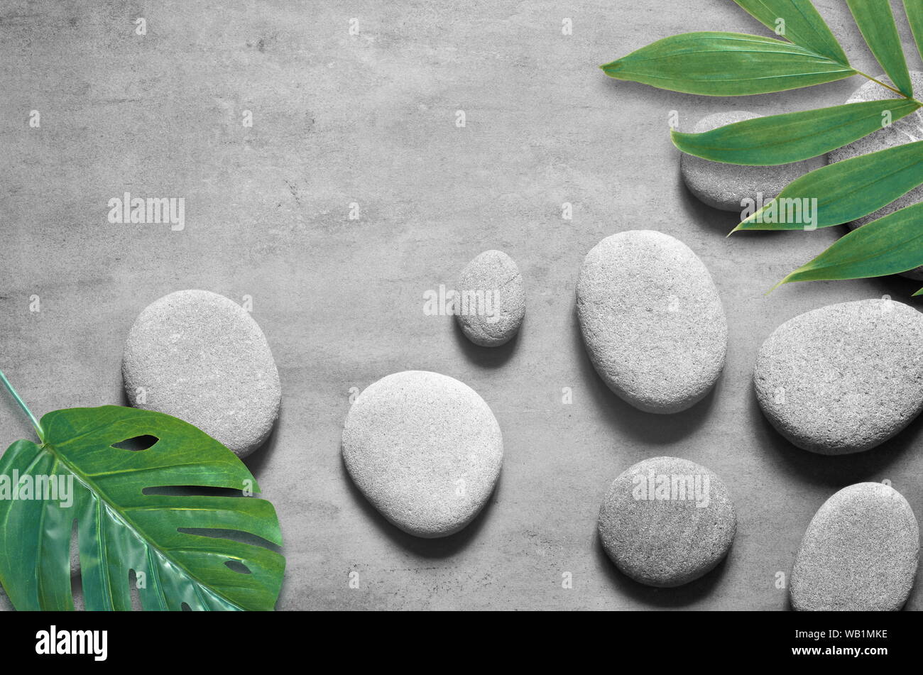 Flat lay composition with spa stones, green palm leaves on grey ...