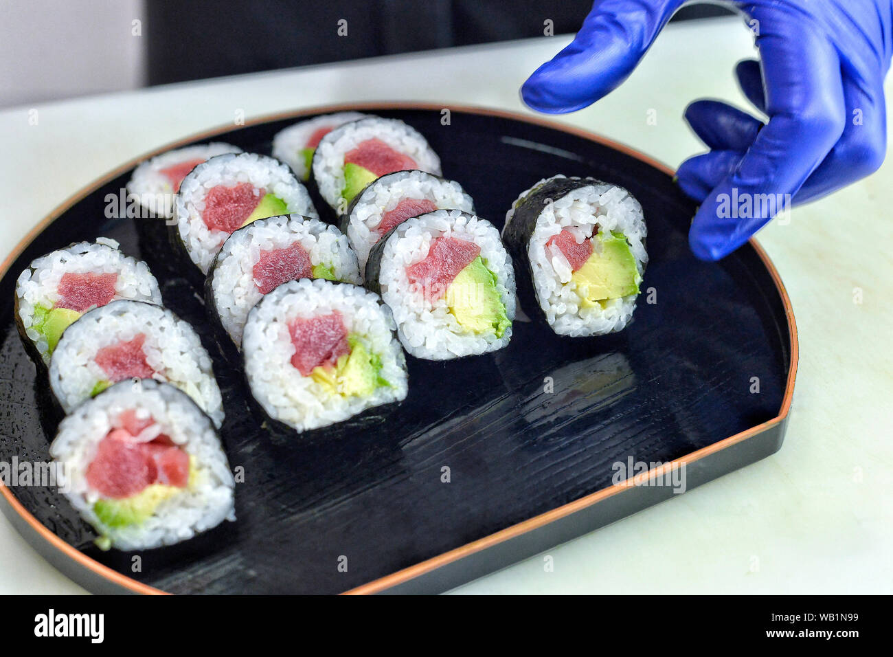 The process of making Japanese sushi. Knife in hand cuts a roll close-up on  a wooden board Stock Photo - Alamy