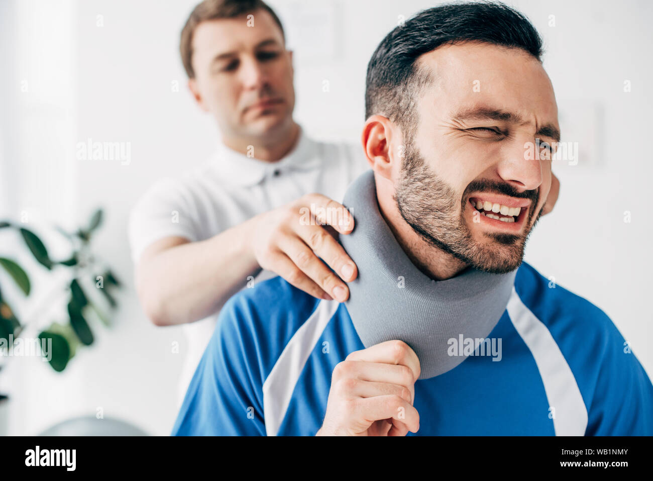 chiropractor examining football player in neck brace in hospital Stock
