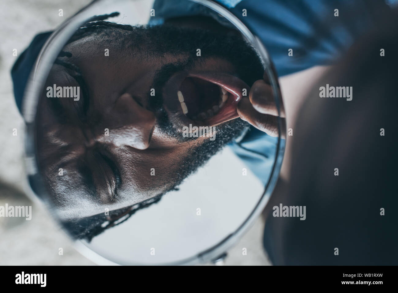 african american man looking at mirror while suffering from toothache Stock Photo
