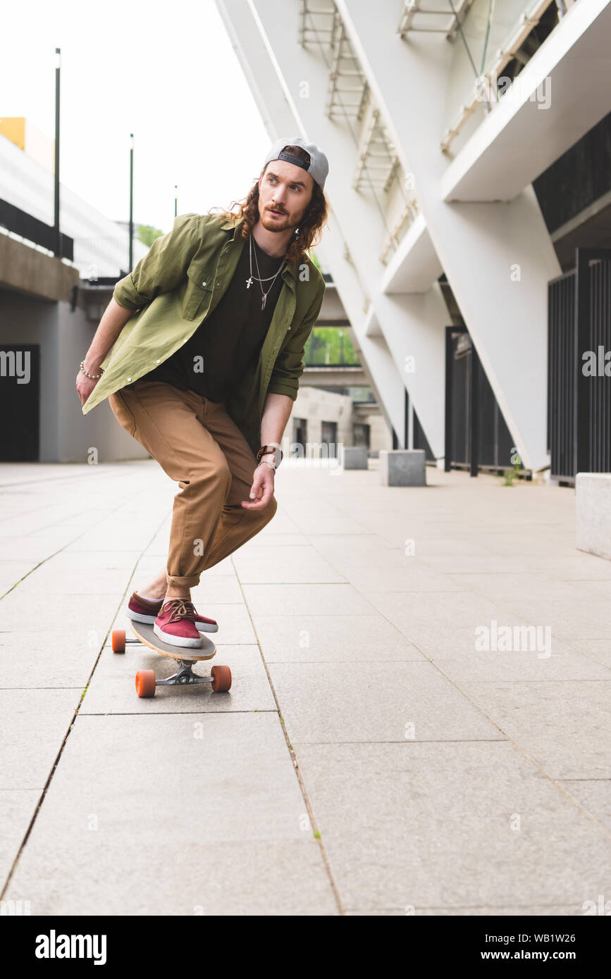 handsome man riding on skateboard in city, looking away Stock Photo - Alamy