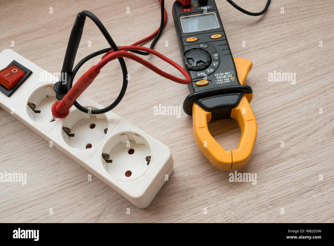 Clamp meter with Power strip on the wooden table Stock Photo