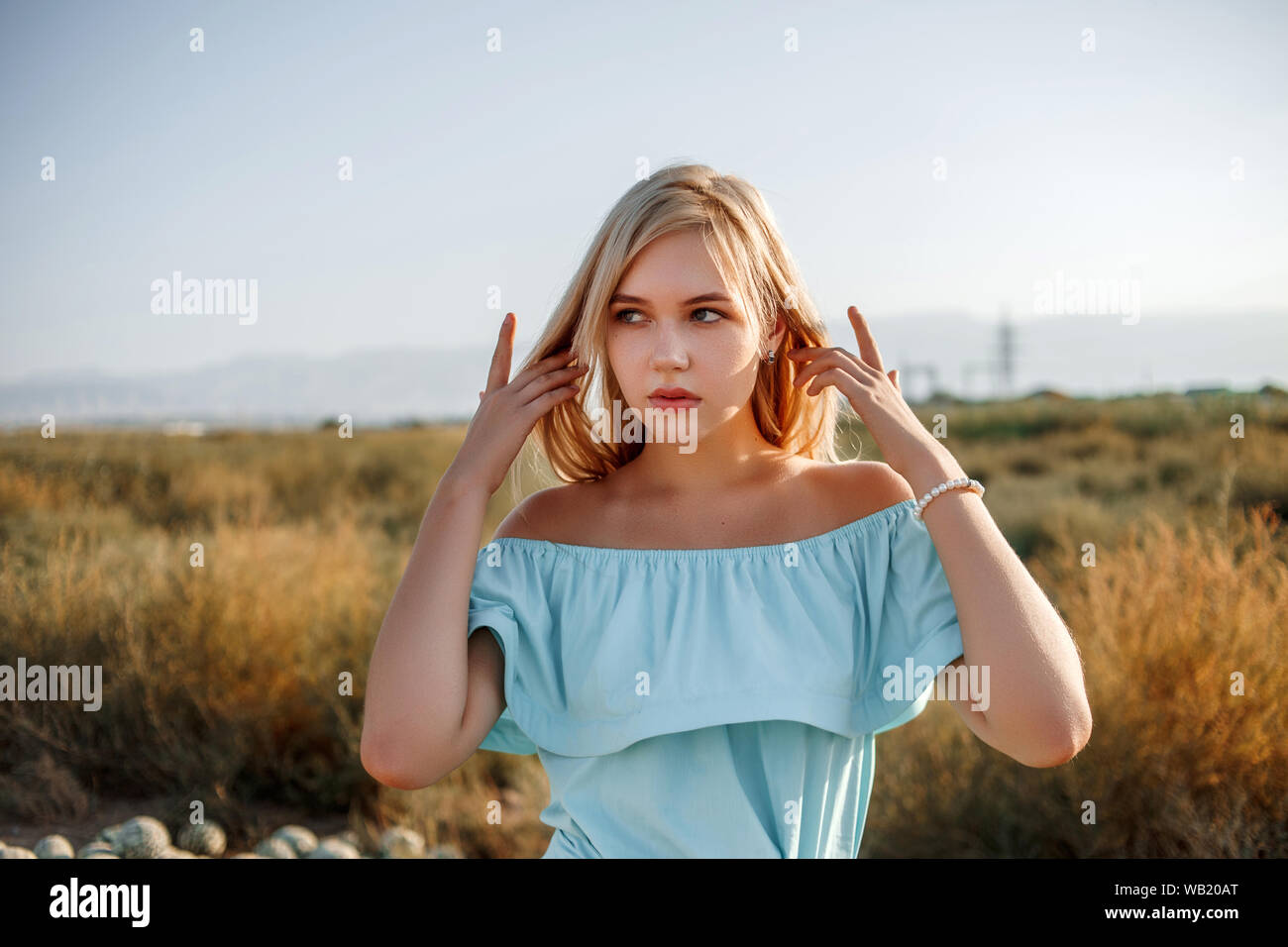 portrait of a young beautiful caucasian blonde girl in a light blue ...