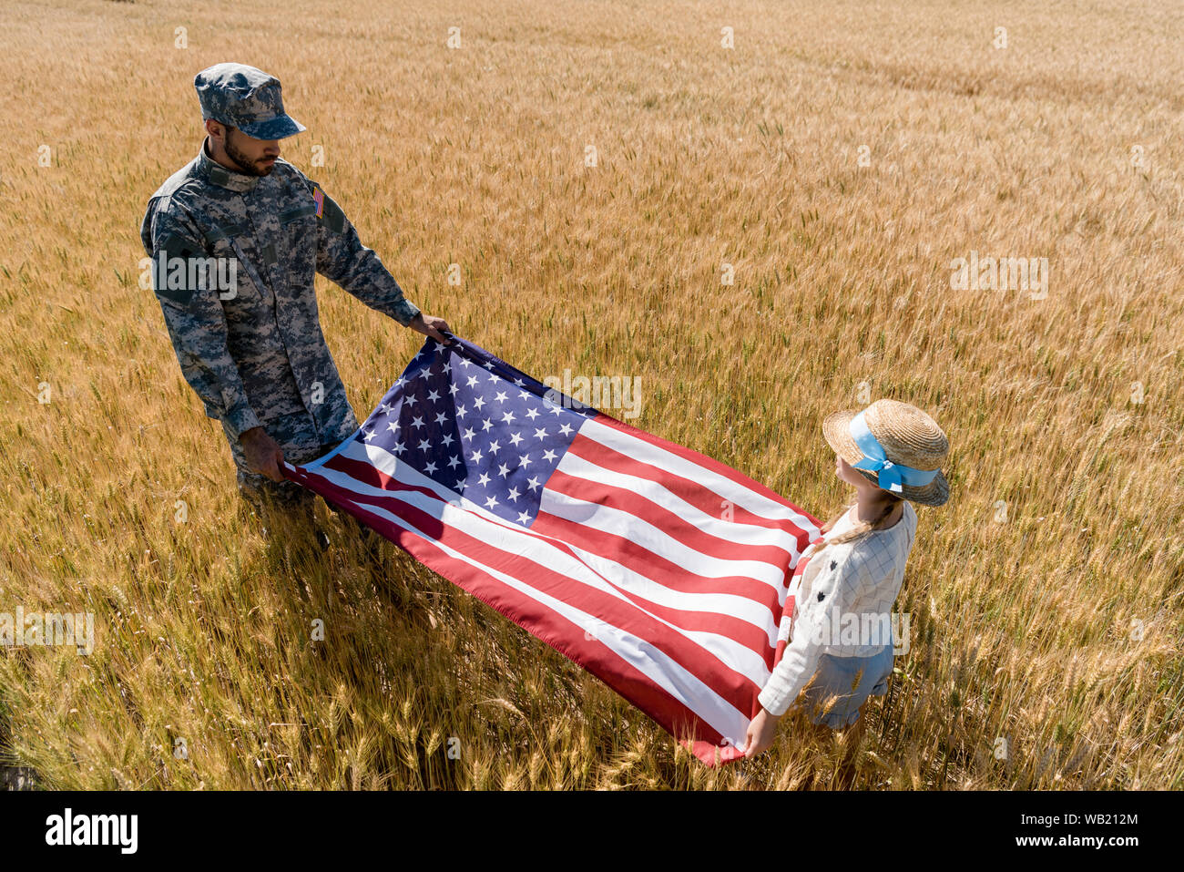 overhead view of soldier in uniform and kid holding american flag in field Stock Photo