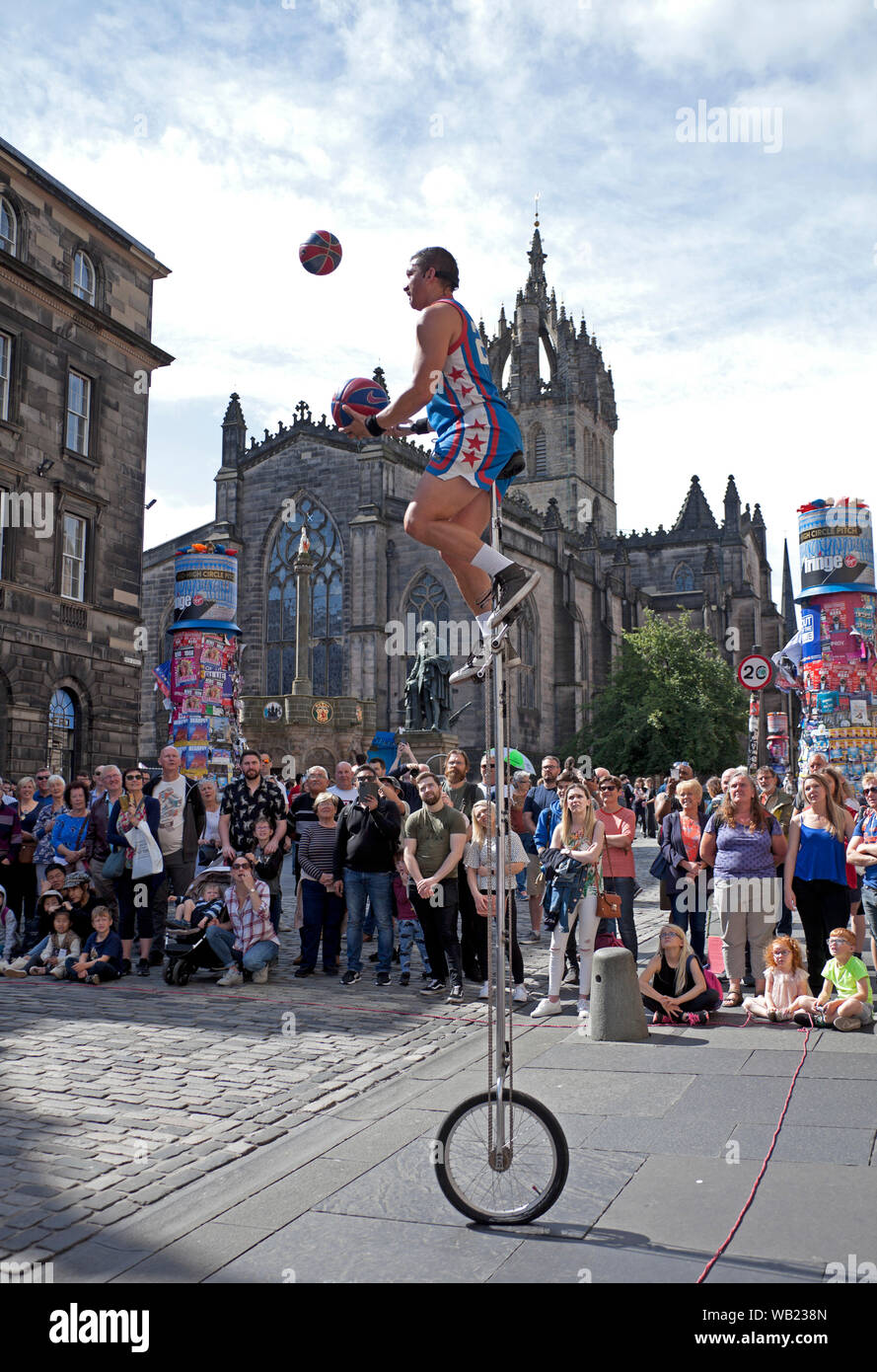 Royal Mile, Edinburgh, Scotland, UK. 23rd August 2019. Basketball Jones juggles balls and a fire torch on the High Street, with St Giles Cathedral in the background. Stock Photo