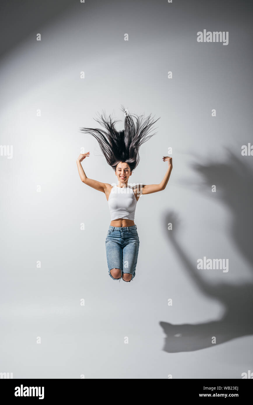 full length view of excited happy girl jumping with hands in air Stock ...
