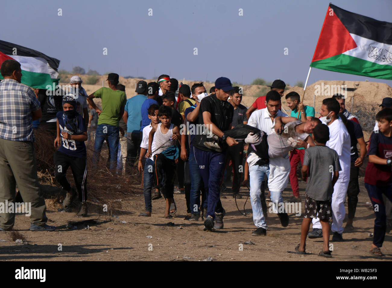Khan Younis, Gaza Strip, Palestinian Territory. 23rd Aug, 2019. A wounded Palestinian protester is evacuated during clashes with Israeli troops following the tents protest where Palestinians demand the right to return to their homeland at the Israel-Gaza border, in Khan Younis in the southern Gaza Strip, August 23, 2019 Credit: Mariam Dagga/APA Images/ZUMA Wire/Alamy Live News Stock Photo