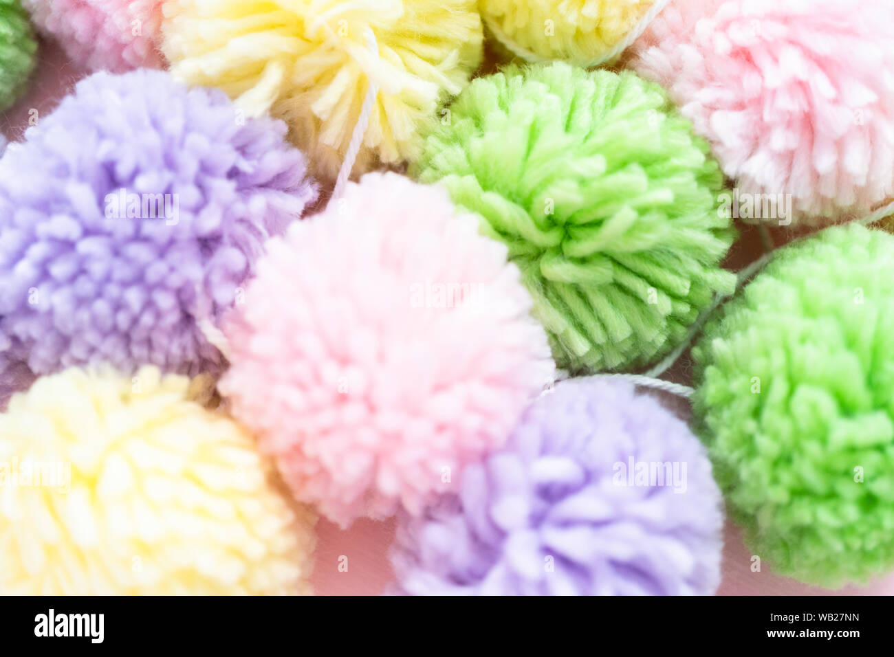 Pastel color pom poms on a pink background Stock Photo