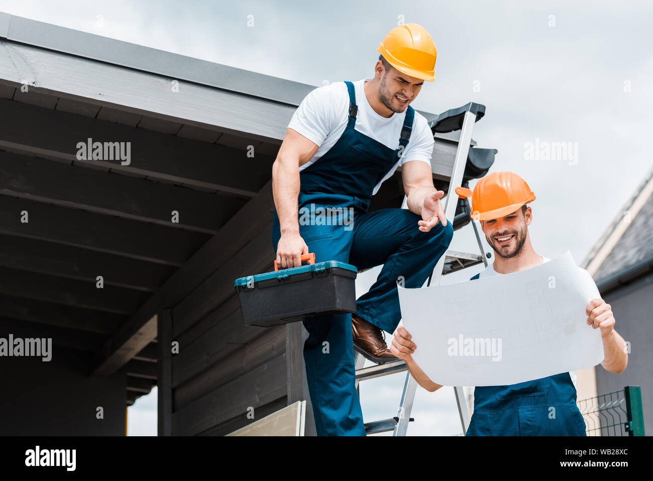 Pointing Near happy architect pointing with finger at paper near coworker Stock Photo ...