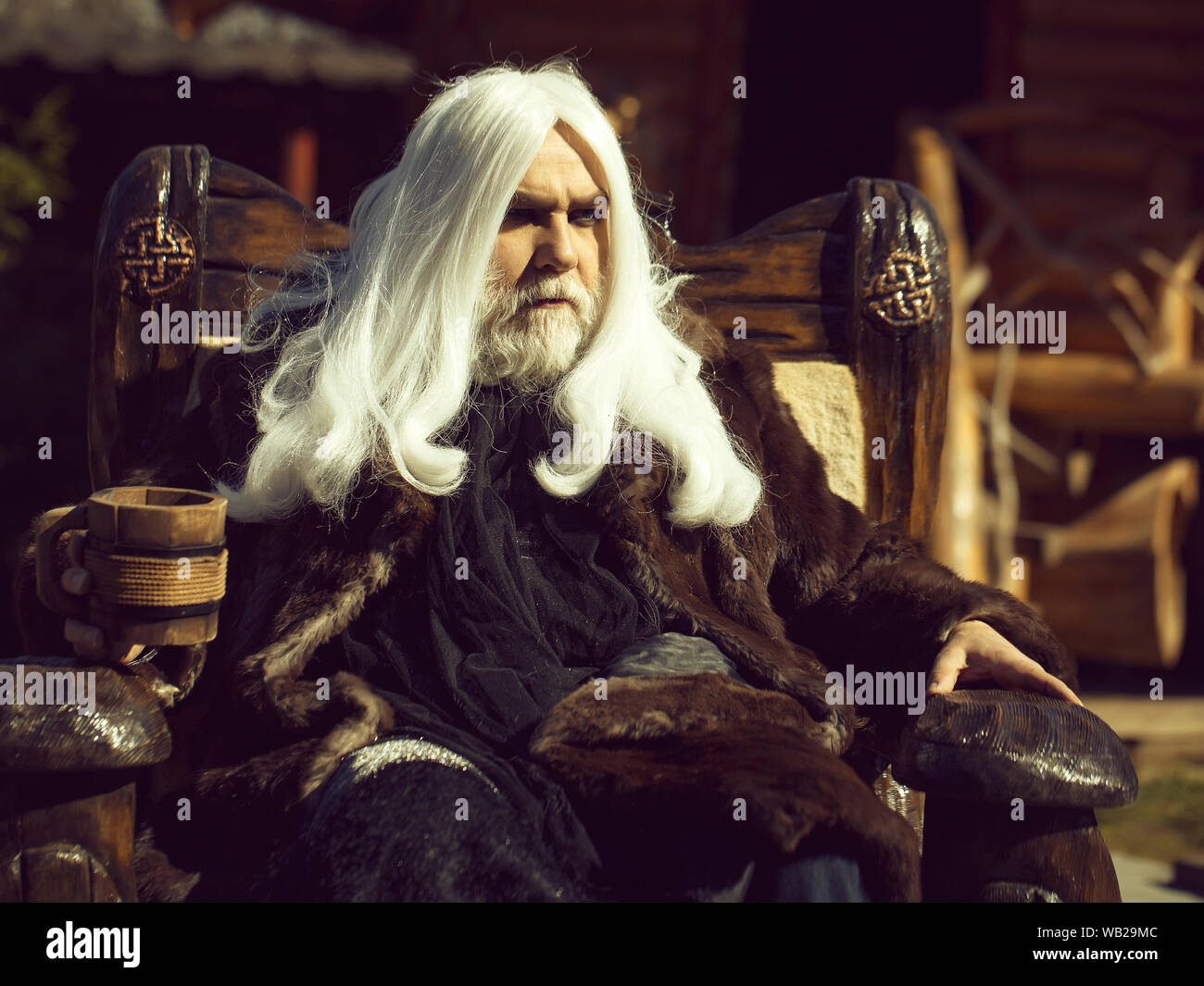 Druid Old Man With Long Silver Hair Beard In Fur Coat Sits In