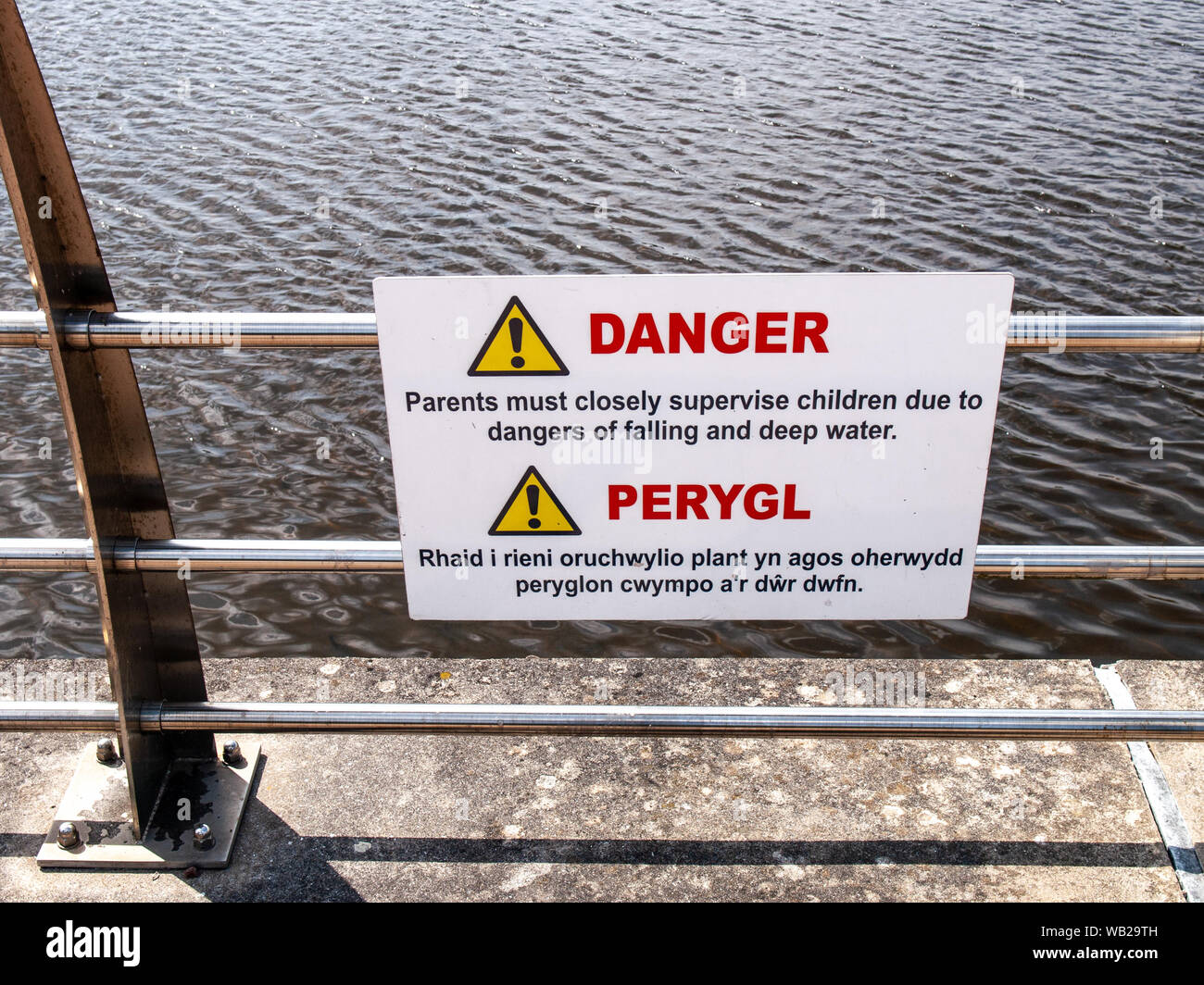 Warning sign about the dangers of falling and deep water at side of the River Tawe in Swansea. Dual language. Welsh/English. Wales, UK. Stock Photo