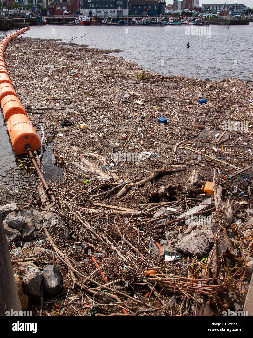 Floating barrier full of rubbish, wood, plastic bottles and flotsam near the the mouth of the River Tawe in Swansea, Wales, UK. Stock Photo