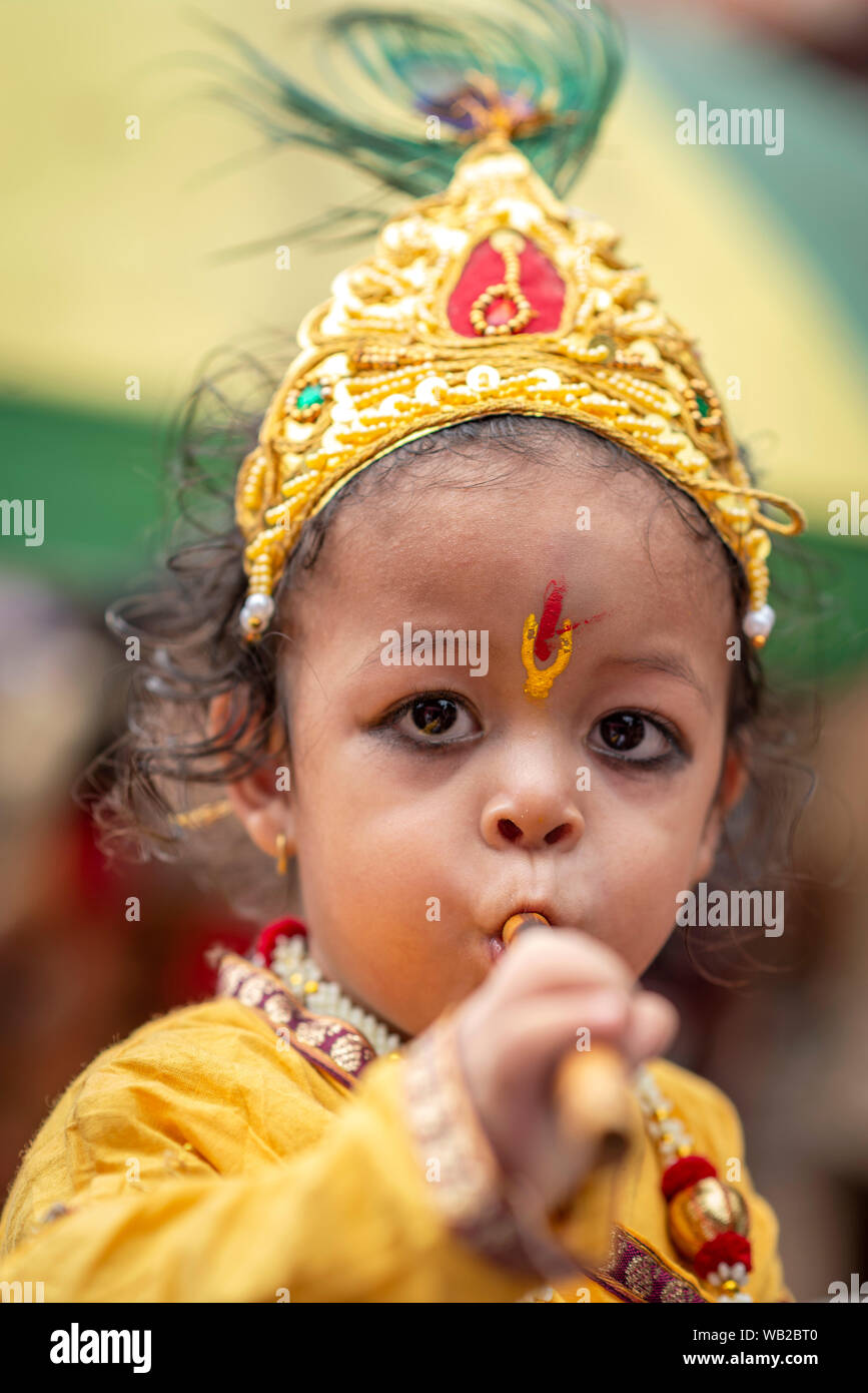 A kid dressed as lord Krishna playing a flute during the ...