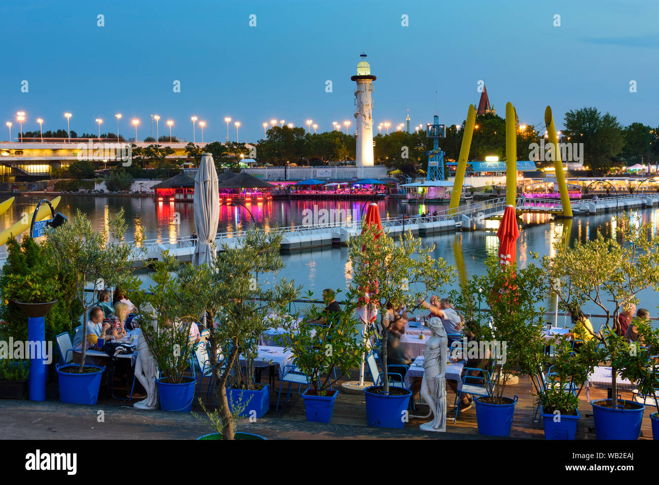 Wien, Vienna: river Neue Donau (New Danube), openair restaurant and bar at Copa Cagrana (front) and Sunken City (back), island Donauinsel, bridge Reic Stock Photo