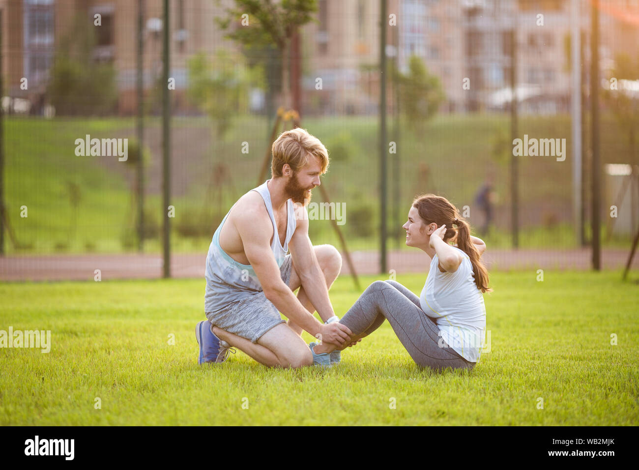Sit ups fitness couple exercising sit up outside in grass. Fit people
