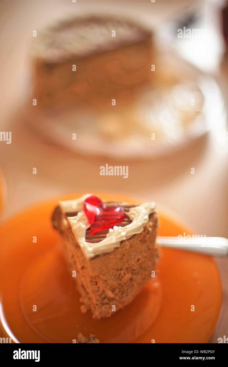 A piece of Kiev cake on an orange plate with a fork Stock Photo