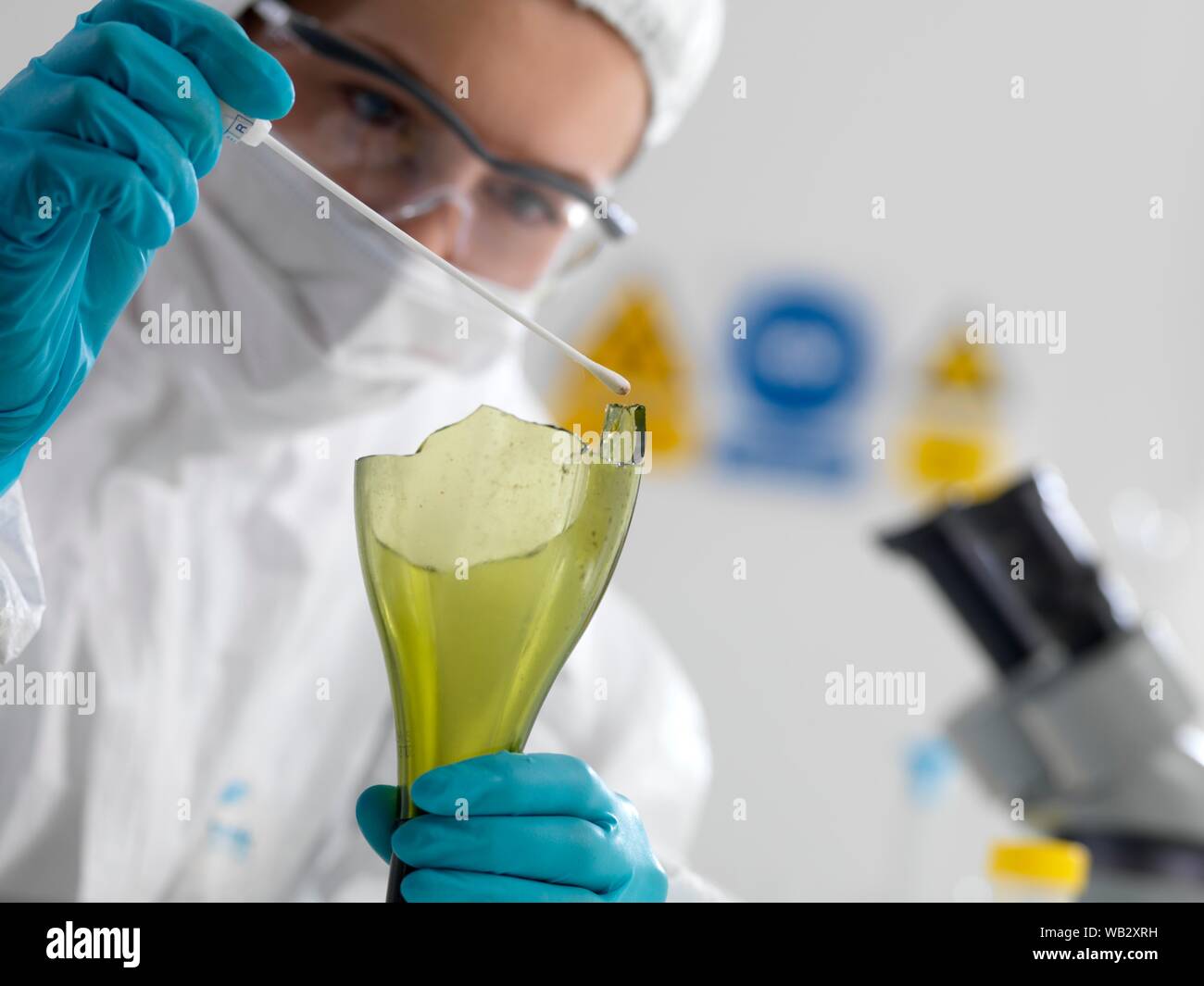 Forensic scientist collecting evidence by taking a DNA (deoxyribonucleic acid) swab from scene of crime bottle. Stock Photo