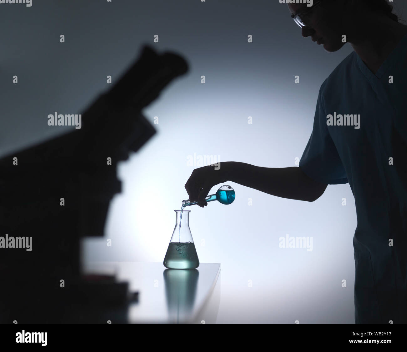 Chemistry research. Scientist pouring a chemical formula into a flask