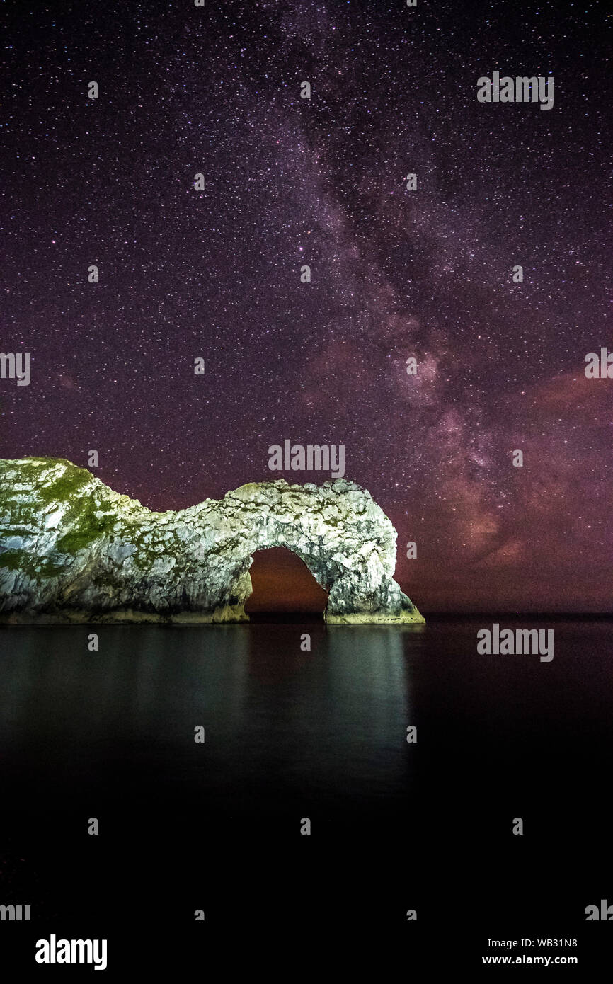 Durdle Door, Lulworth, Dorset, UK.  23rd August 2019.  UK Weather:  The Milky Way shines brightly in the clear night sky above the limestone sea arch of Durdle Door on the Dorset Jurassic Coast.  Picture Credit: Graham Hunt/Alamy Live News Stock Photo