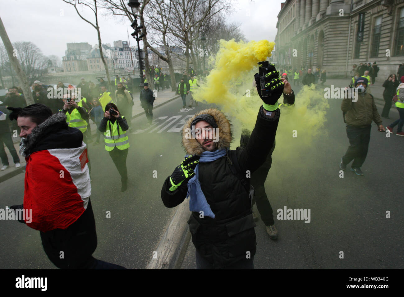 Demonstrators wearing yellow vest send yellow smoke into the air during march a protest in Paris on January 5, 2019 in Paris,France. Thousands of demo Stock Photo
