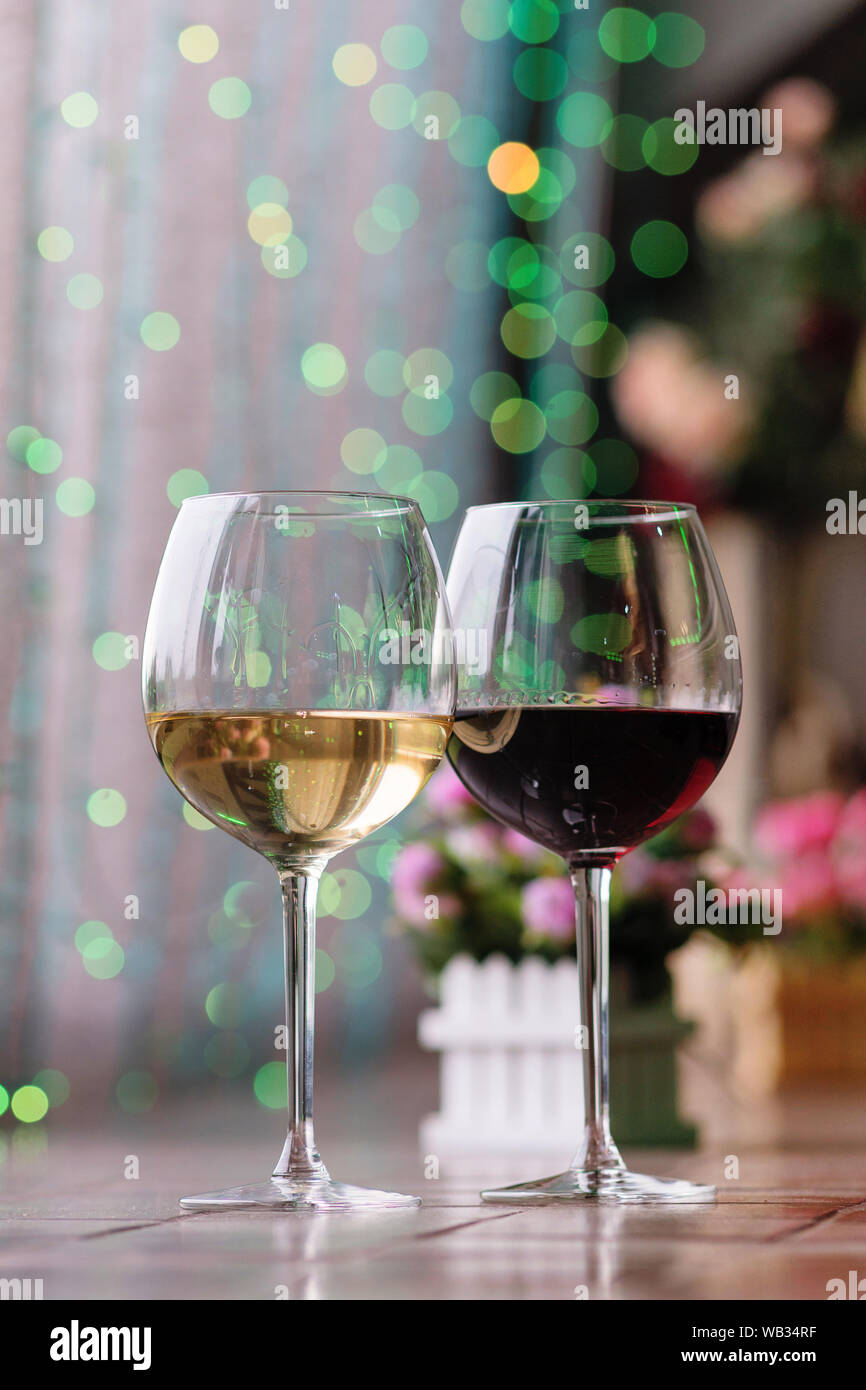 Two glasses of wine white and red standing on a table. Colorful bokeh ...