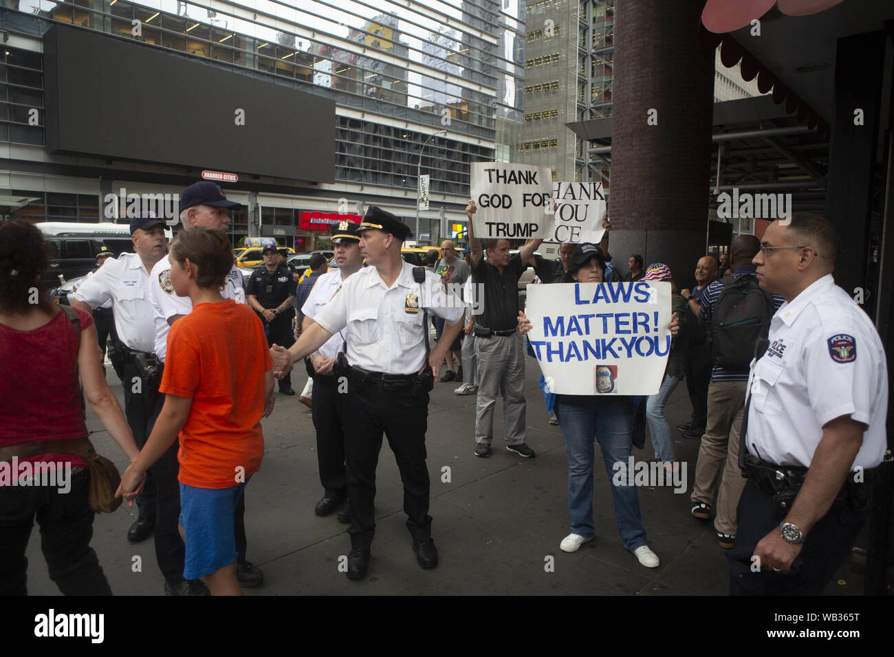 August 23, 2019: New York Police officers stands in front anti-protestors during a protest against Greyhound Corporation and ICE (Immigration Customs and Enforcement) at the Port Authority Bus Terminal on 42nd and 8th Avenue in New York, New York. About 100 activists from a coalition of groups including FIRE (Fight For Immigrant Refugees Everywhere) protested Greyhound allowing ICE agents to board their busses 'searching for migrants,'' officials said. Credit: Brian Branch Price/ZUMA Wire/Alamy Live News Stock Photo
