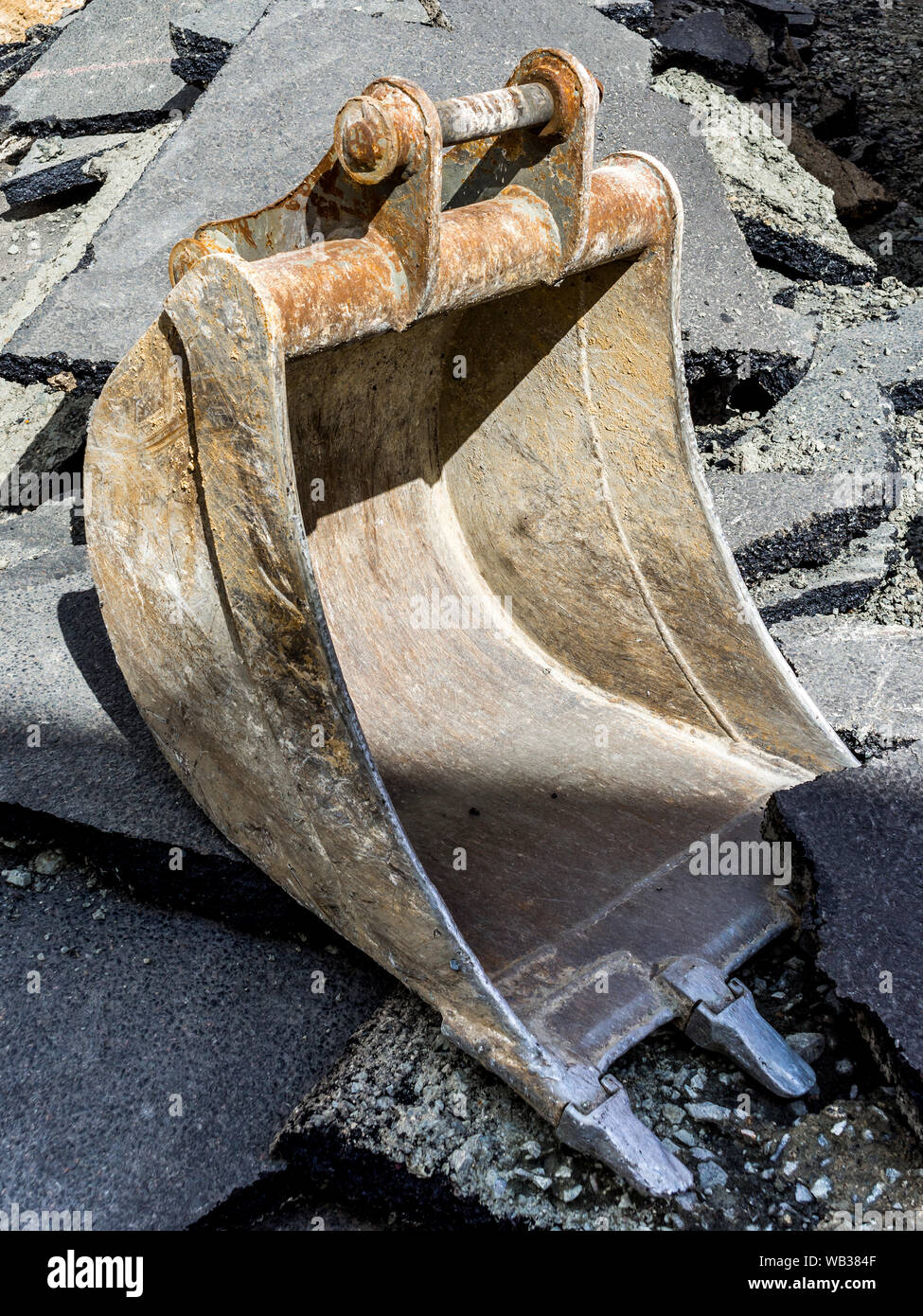 Digger bucket and broken road surface. Stock Photo