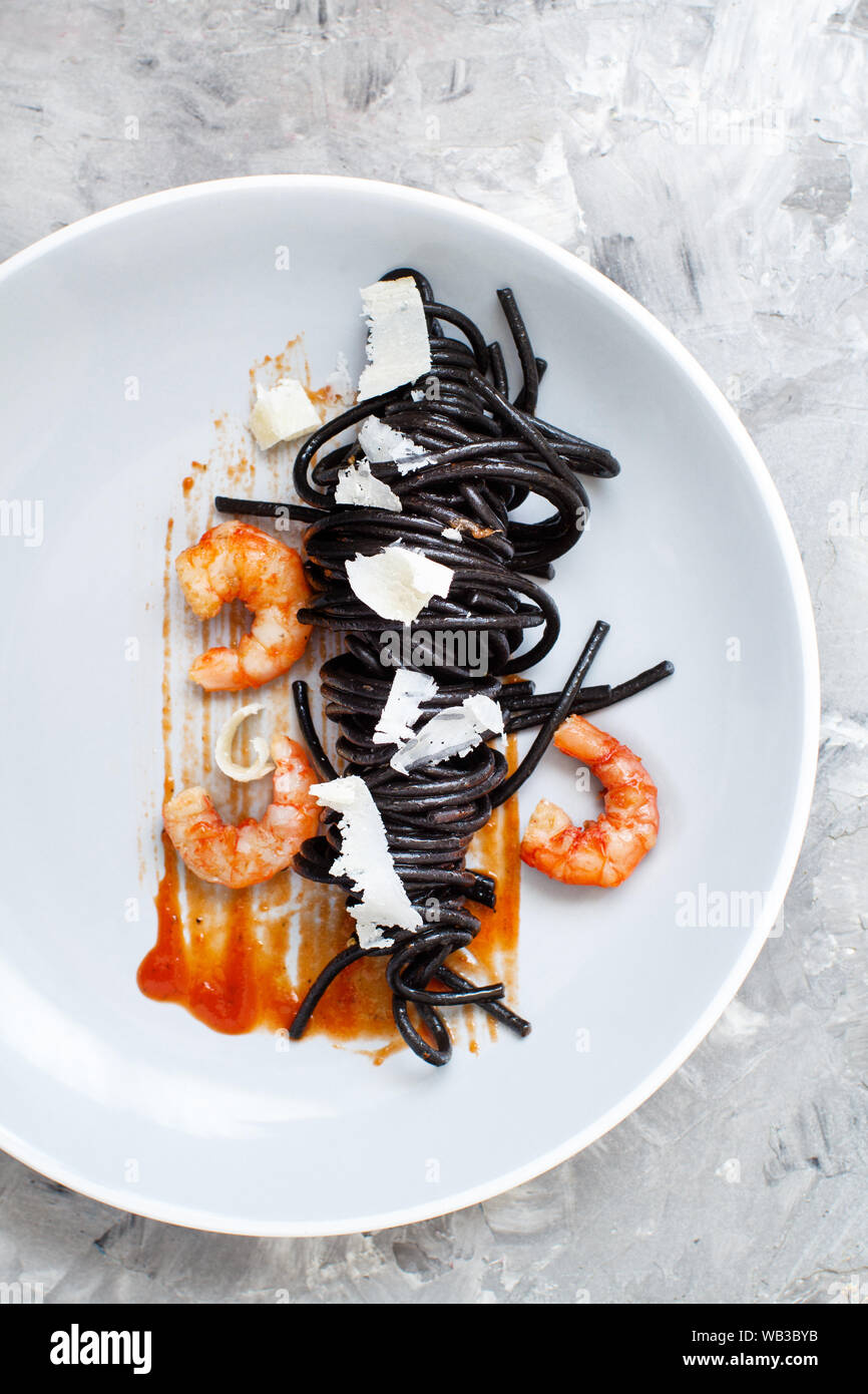 Squid ink black spaghetti with prawns and tomatoes top view Stock Photo