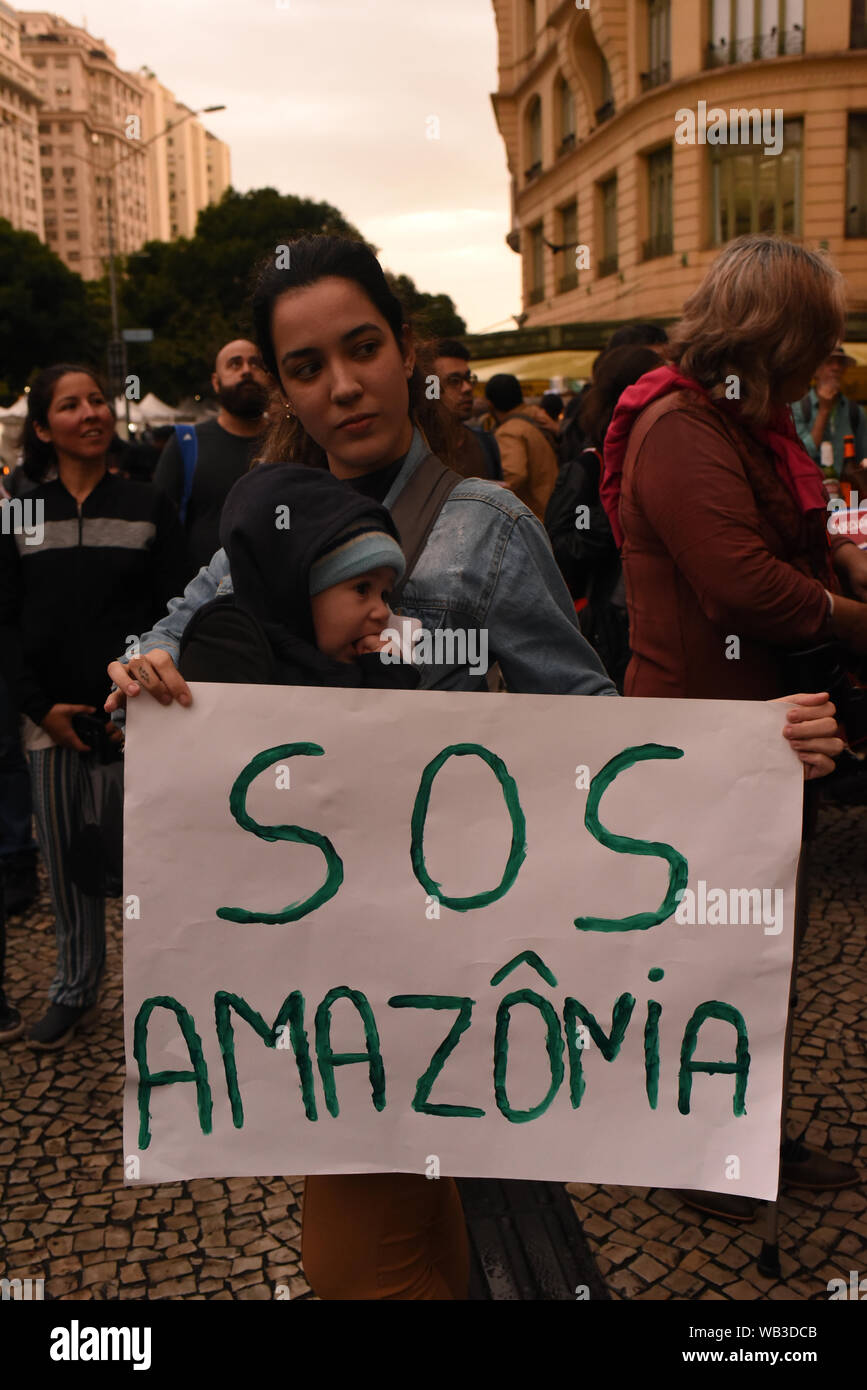 Rio De Janeiro, Brazil. 23rd Aug, 2019. A woman with a baby holds a sign with the inscription 'SOS Amazonia' ('SOS Amazonien') at a demonstration in view of the devastating forest fires in the Amazon. In Brazil, the worst forest fires in years are currently raging. Since January 2019, fires and slash-and-burn in South America's largest country have increased by 83 percent compared to the same period last year. Credit: Fabio Teixeira/dpa/Alamy Live News Stock Photo