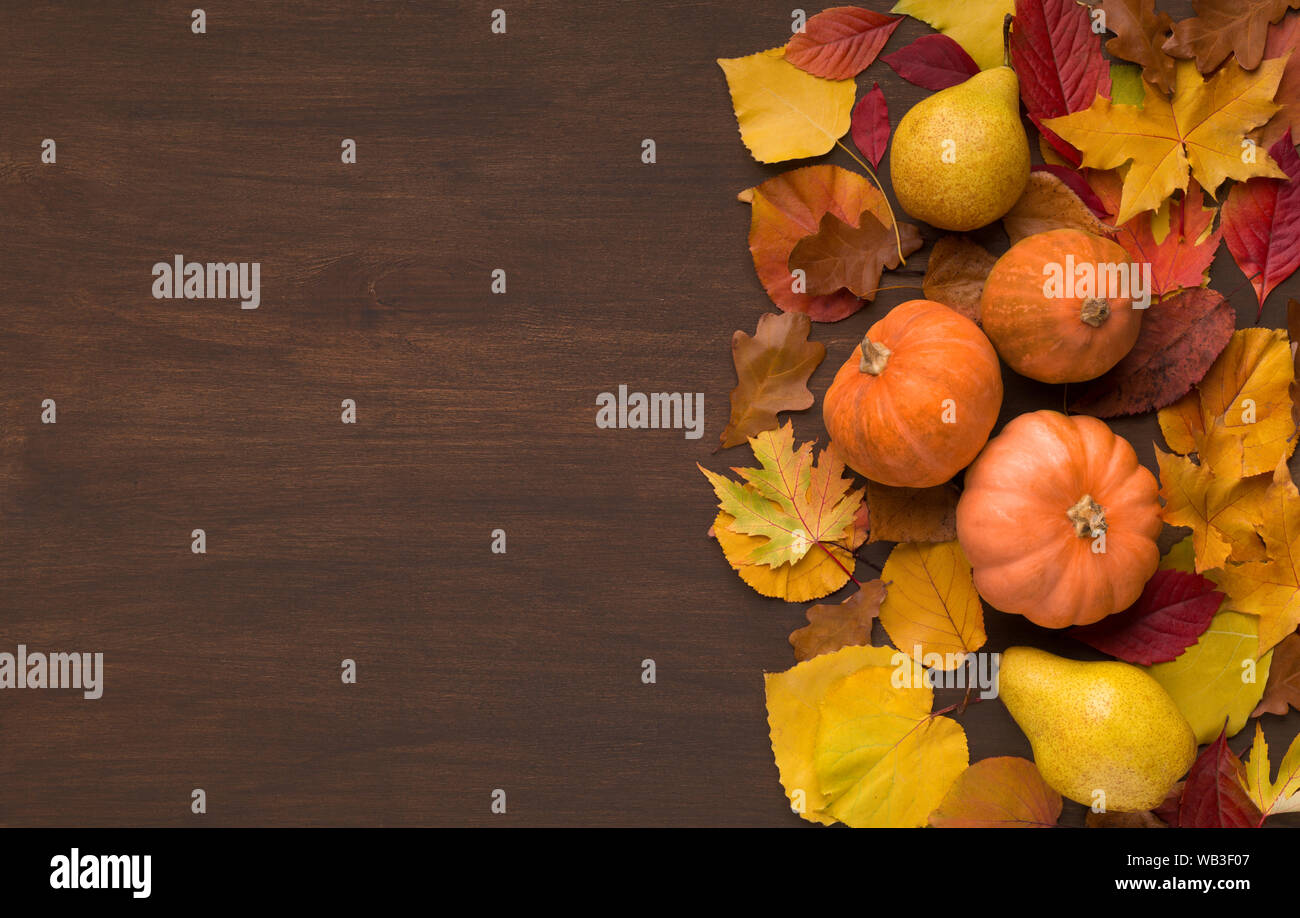 Autumn foliage with three decorative pumpkins on wood Stock Photo