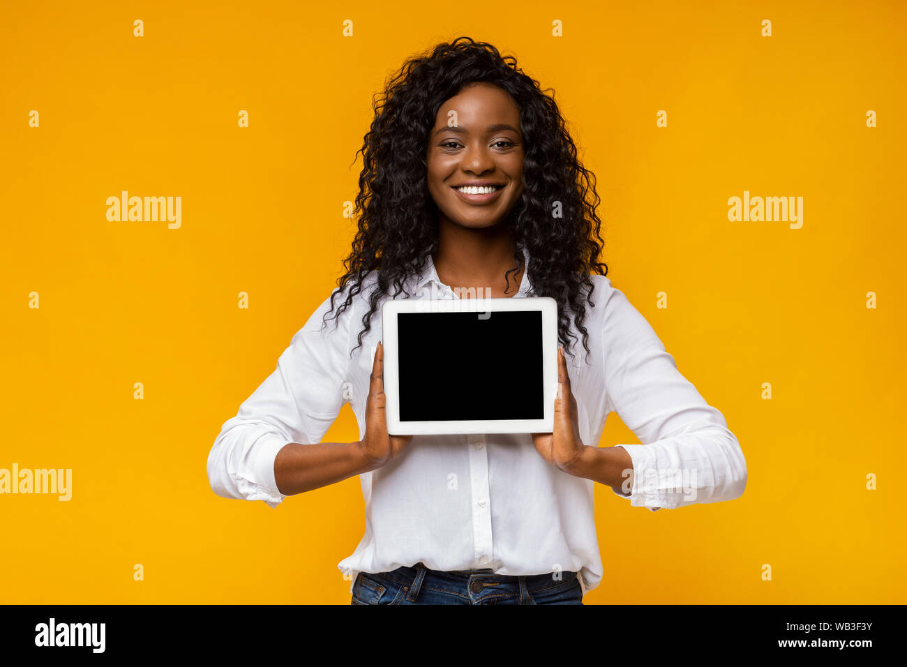 Afro smiling woman demonstrating blank digital tablet screen Stock ...