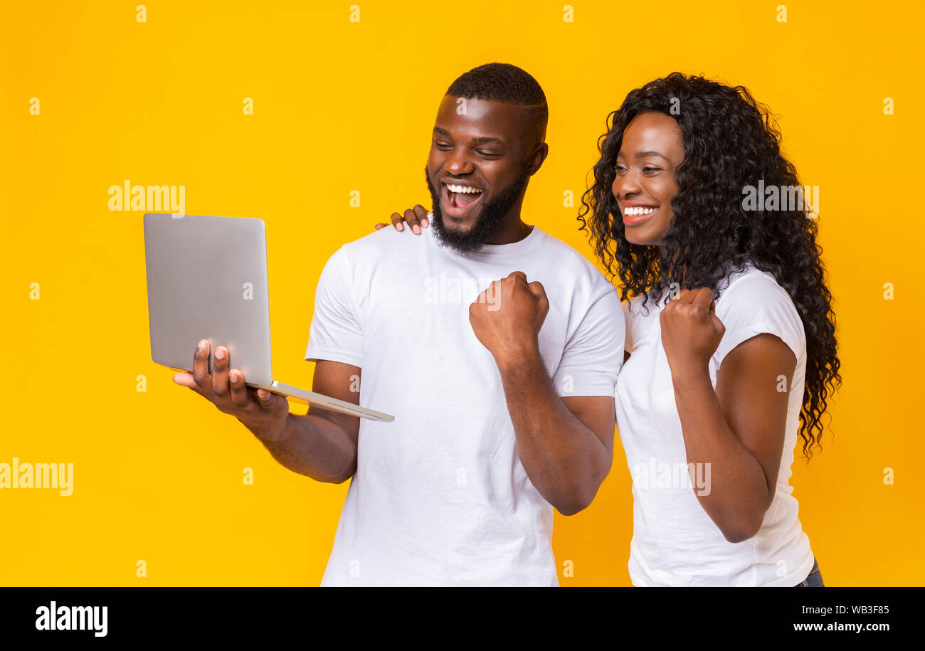 Happy black couple celebrating success with laptop Stock Photo - Alamy